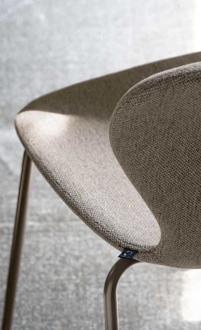 Sedia elegante con tessuto morbido e gambe sottili, atmosfera di comfort e modernità.